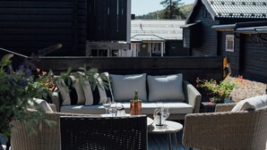 A rooftop patio with wicker furniture, a sofa, and a table with a bottle and glasses.