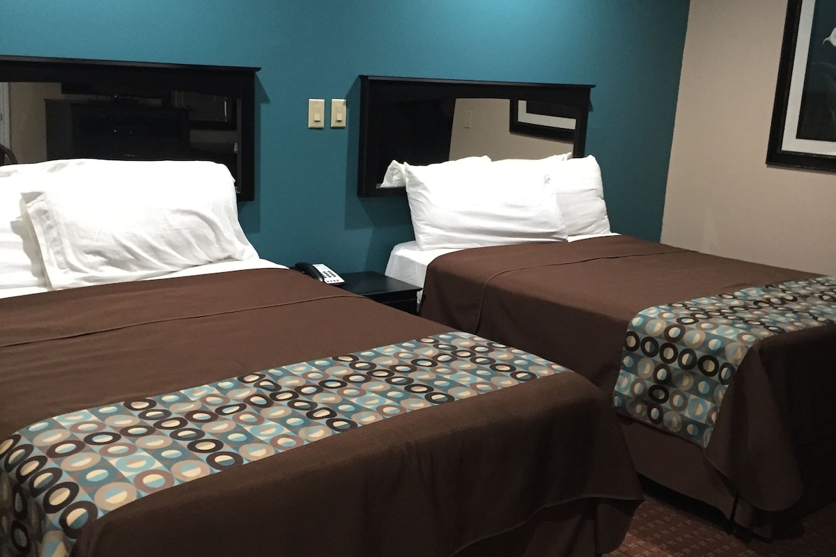 A hotel room with two beds, a nightstand, a telephone, and a wall-mounted TV.
