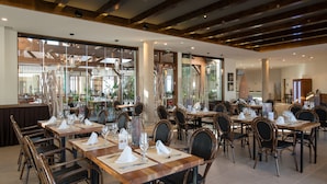 Un restaurante con varias mesas dispuestas, con servilletas blancas, copas de vino y cubiertos.