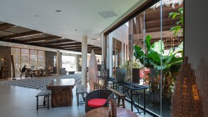 Un espacio interior amplio con un gran ventanal, muebles de madera y vistas al exterior.