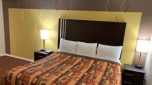 Ein Hotelzimmer mit einem großen Bett, zwei Nachttischen, einem Kopfteil und einer gemusterten Bettdecke.