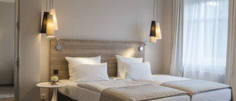 A modern hotel room with a large bed, bedside tables, a round mirror, and a decorative rug.