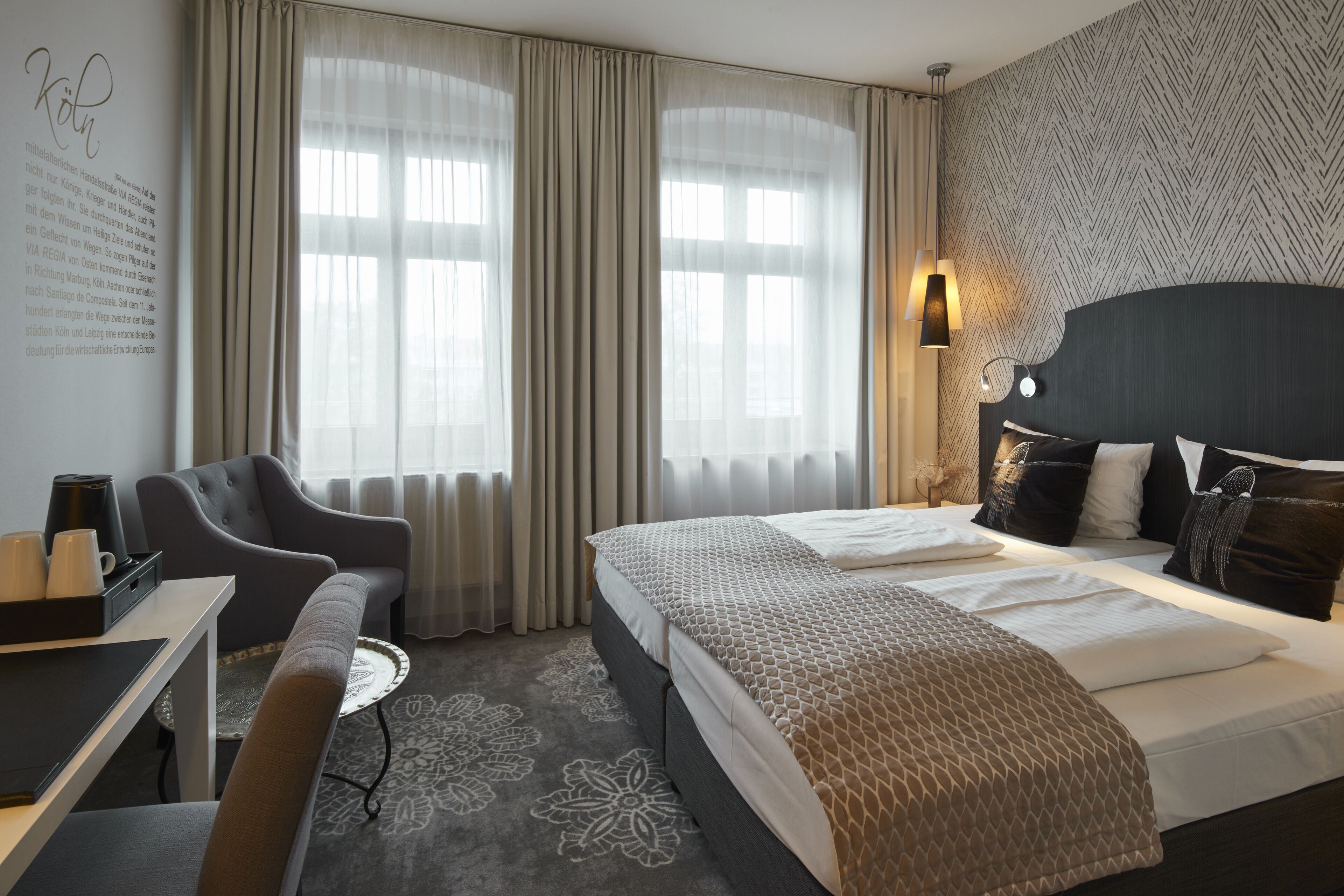 Une chambre d’hôtel avec un lit, un bureau, une chaise et une lampe.