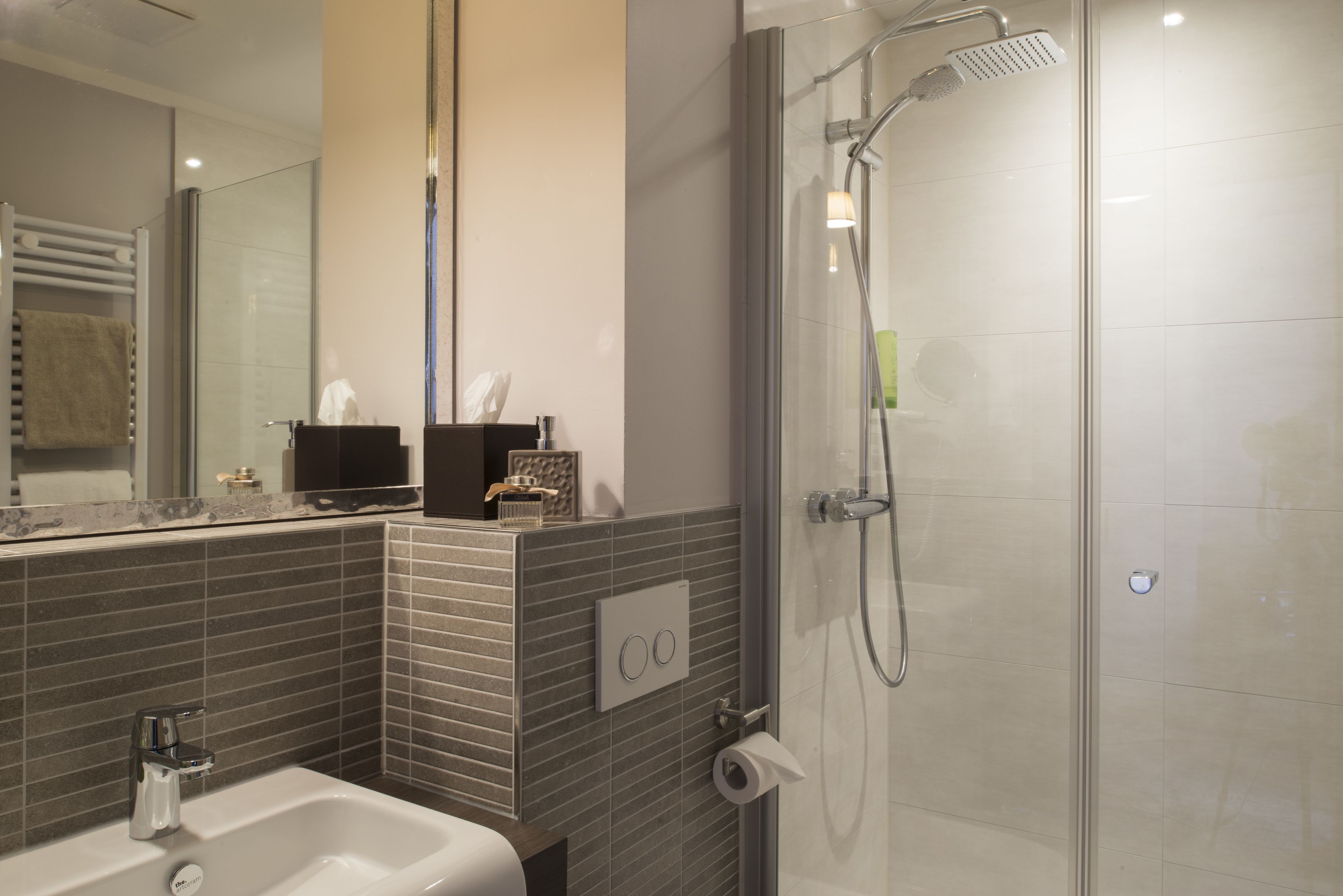 A modern bathroom with a glass-enclosed shower, a sink, and a mirror.
