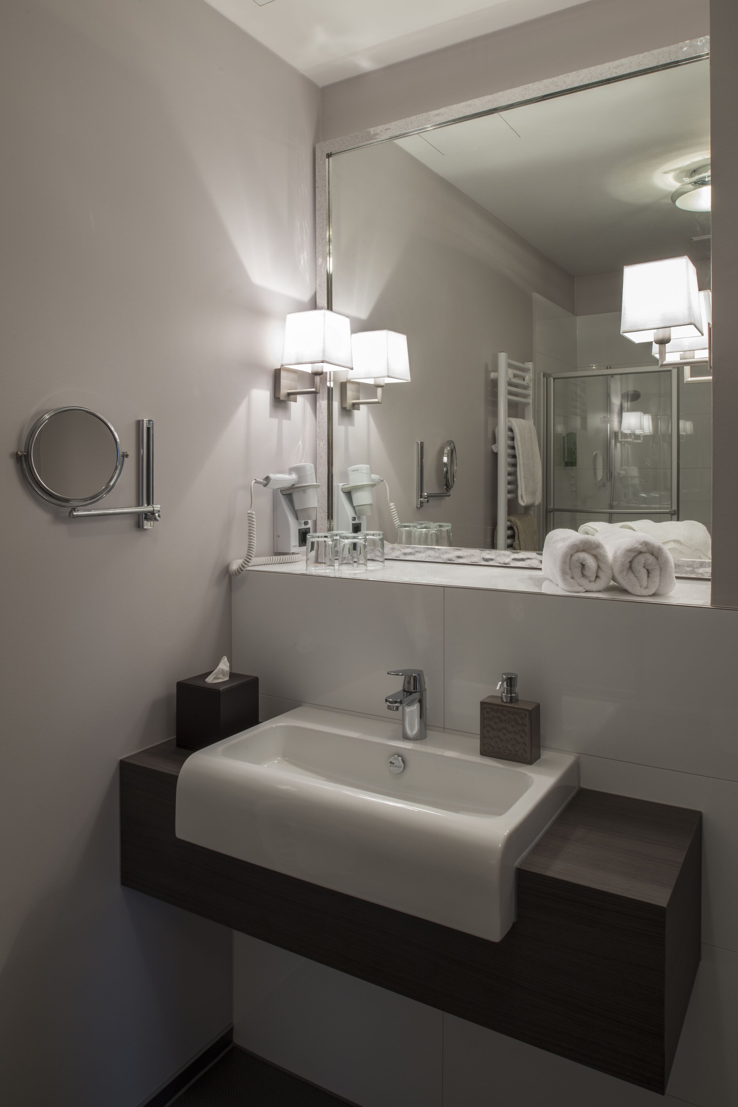 Un baño moderno con un espejo grande, un lavabo y un perchero para toallas.