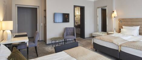 A hotel room with two beds, a desk, a chair, a TV, and a small table.