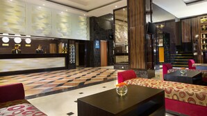 Un hall de hotel con mostrador de recepción, zona de estar y una escalera.