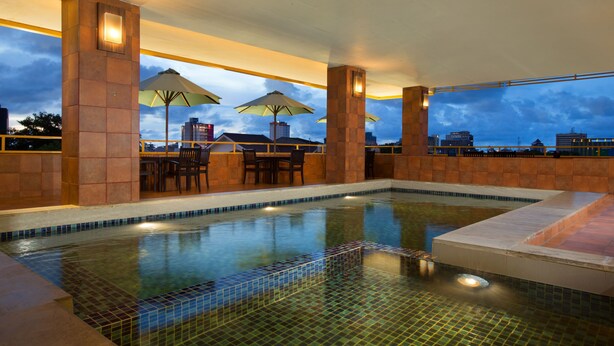 Una piscina interior con suelo de baldosas, zonas de estar y sombrillas.