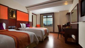 A hotel room with two beds, a desk, and a chair.