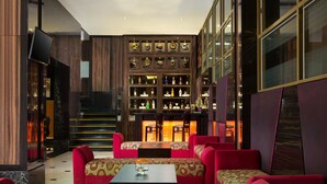 Un lobby moderno con zona de bar, asientos tapizados en rojo y una exhibición de trofeos.