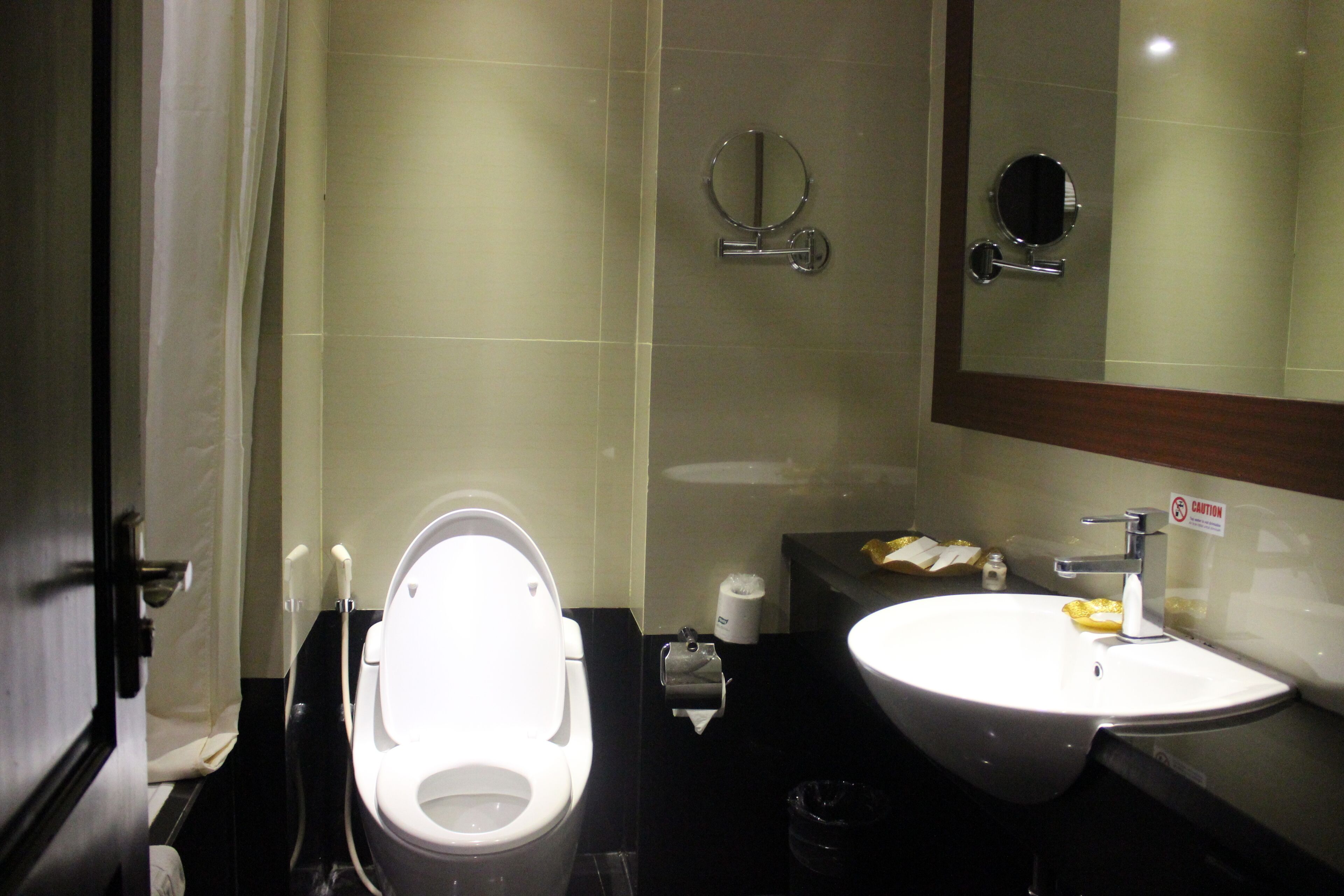 A bathroom with a toilet, sink, and mirror.