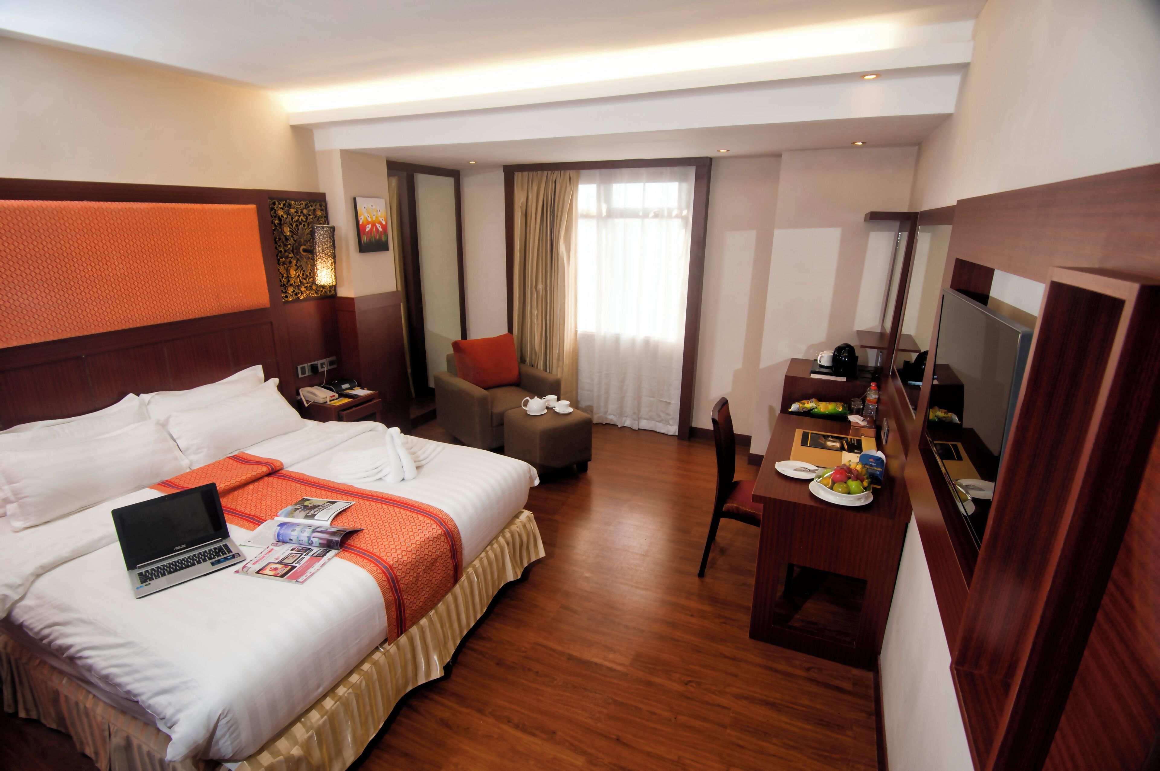 Une chambre d’hôtel avec un grand lit, un bureau, une chaise, un ordinateur portable et une télévision.