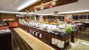Un área de bufé con diversas estaciones de comida, disposición de mesas y un diseño interior moderno.