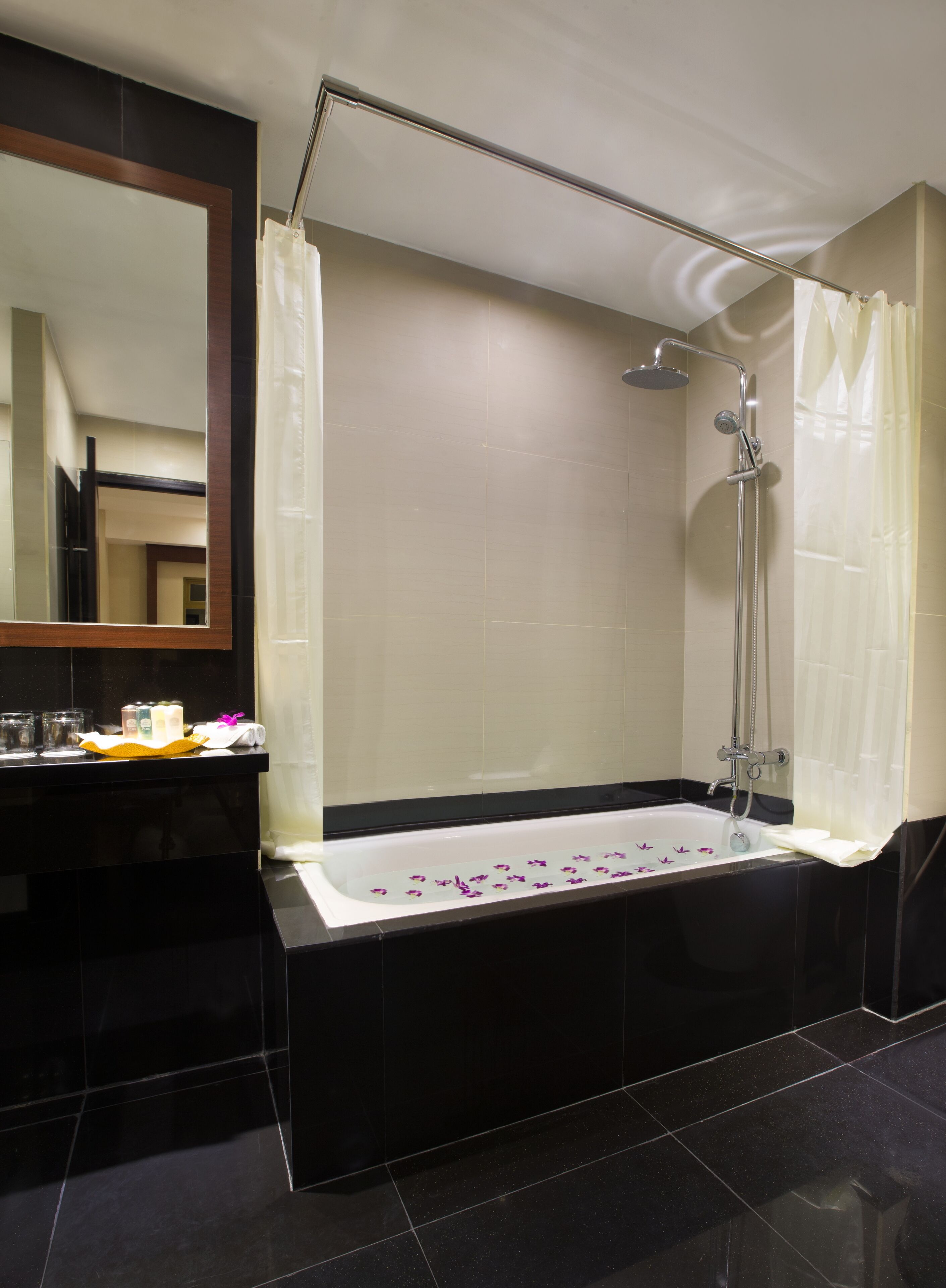 A modern bathroom with a large bathtub, a shower, and a vanity with toiletries.