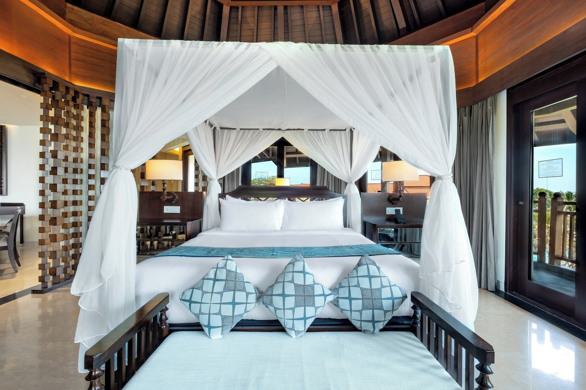 A four-poster canopy bed with a view of the outdoors.
