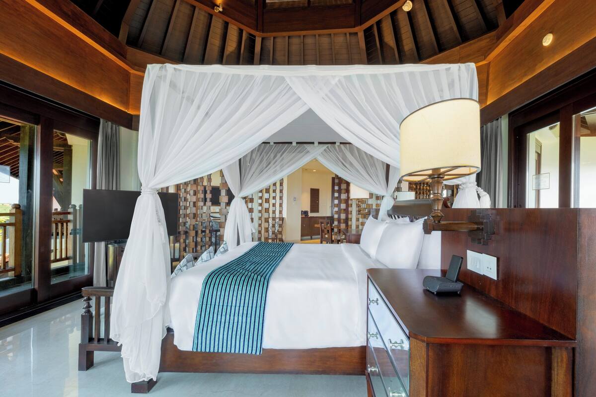 A spacious bedroom with a large bed, a canopy, a desk, and a TV.