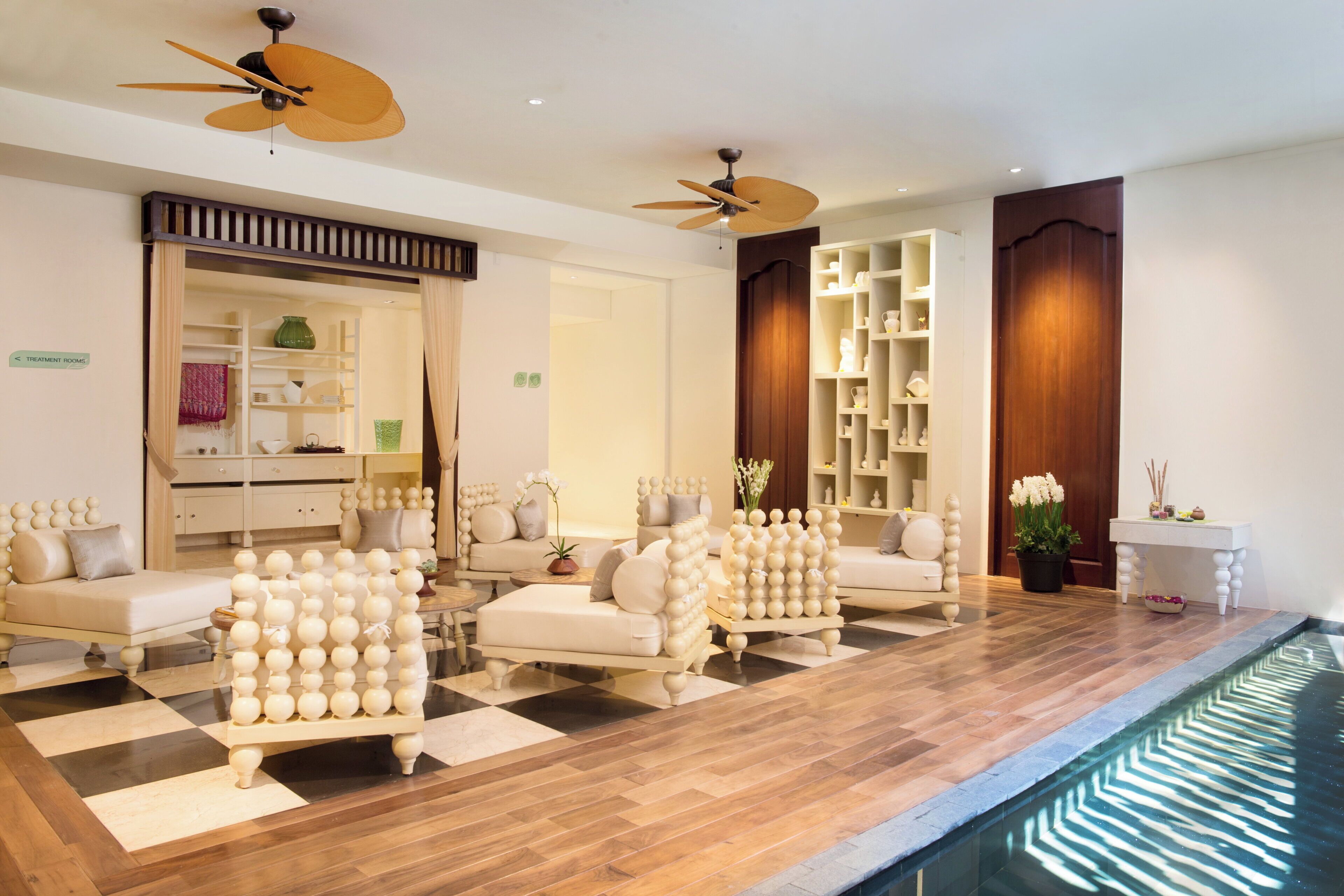 Un hall de hotel con piso a cuadros, sofás, mostrador de recepción y zona de piscina.