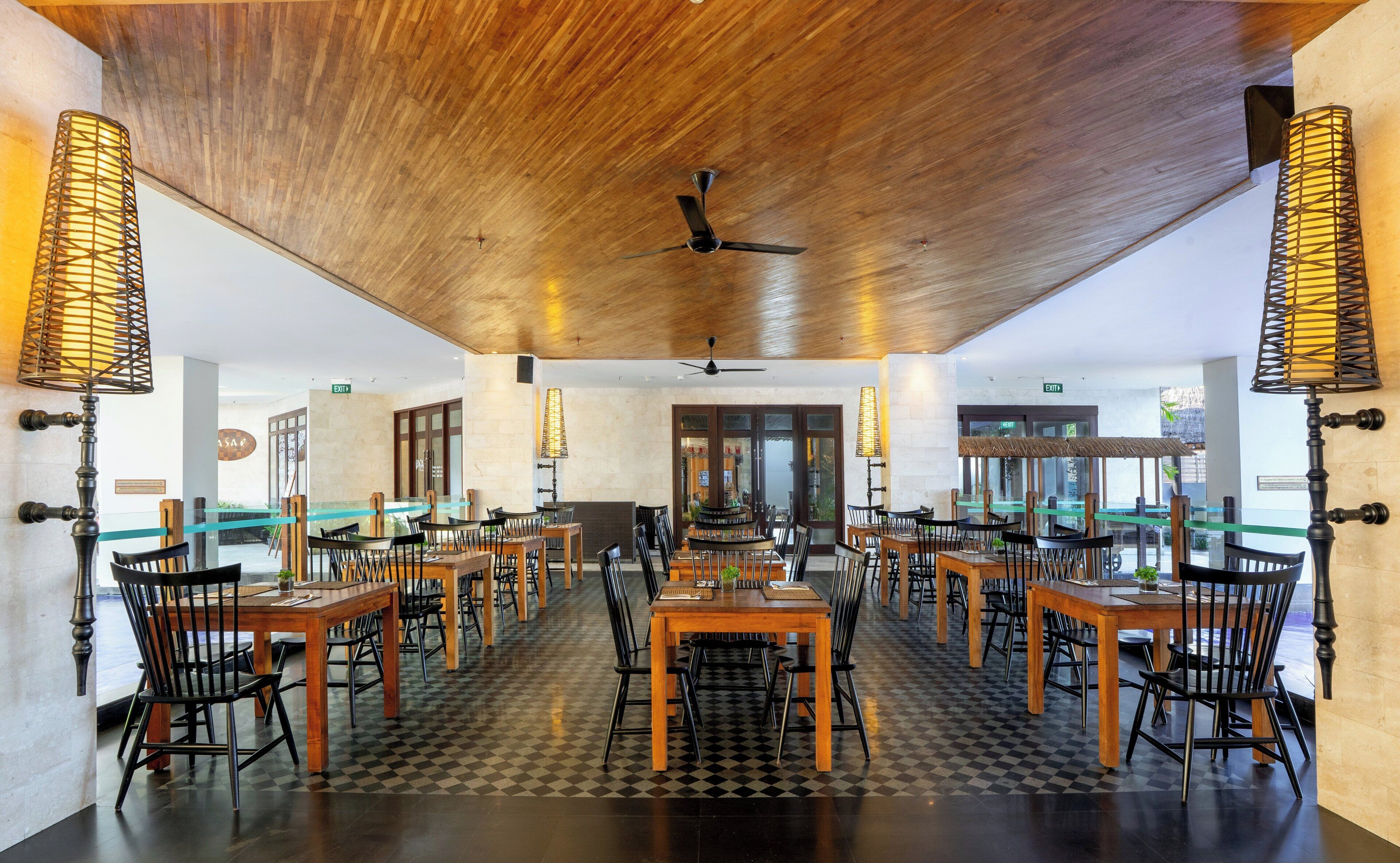 A spacious indoor dining area with wooden tables and chairs, a checkered floor, and a wooden ceiling.