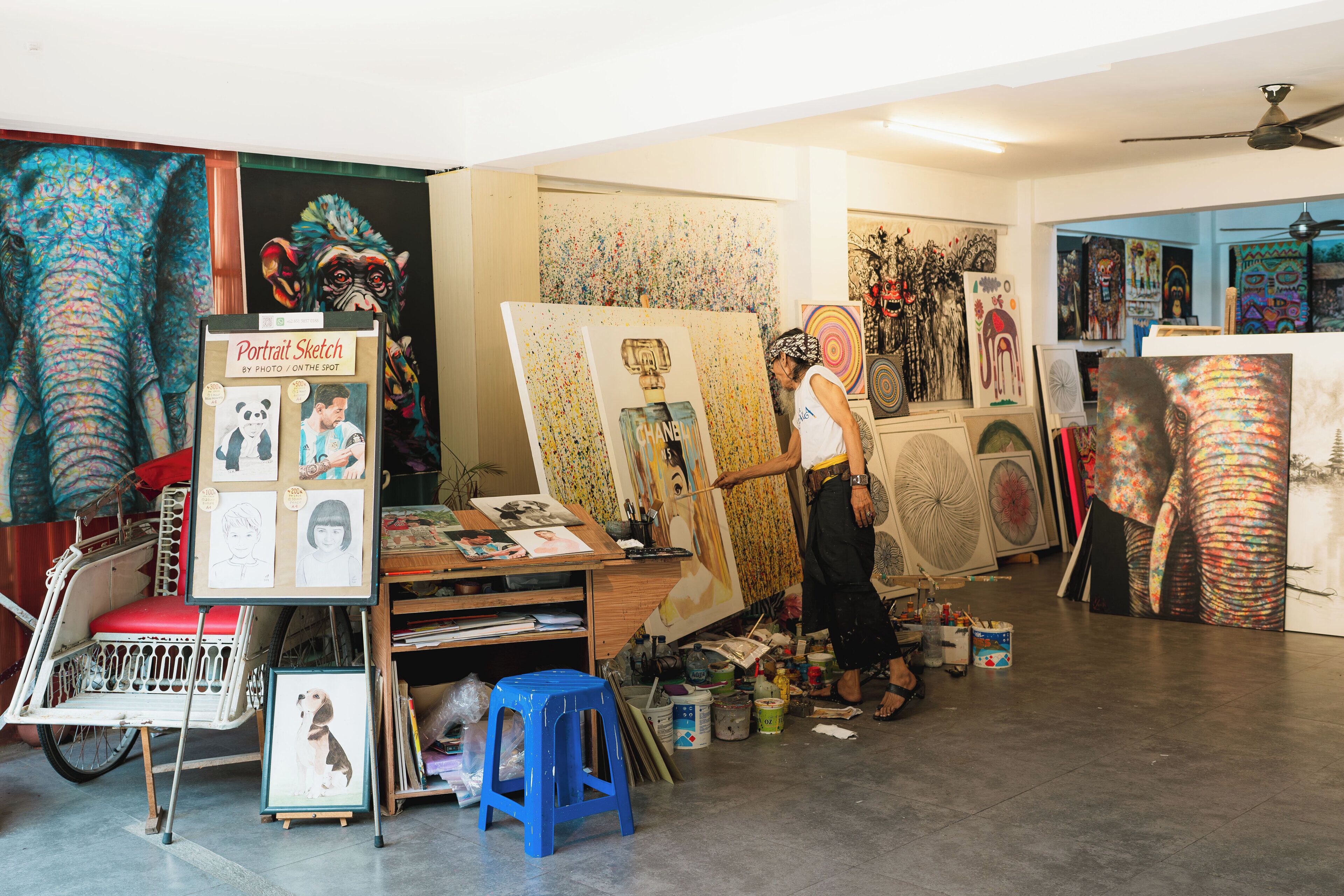 Un estudio de artista con varias obras de arte, una silla en forma de bicicleta y material de arte.