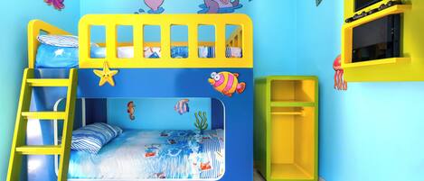 A child's bunk bed with a sea-themed design, including a ladder, a TV shelf, and a small shelf unit.