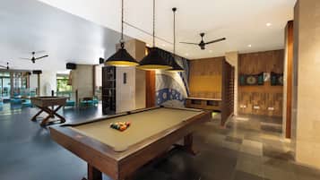A pool table in a spacious room with ceiling fans and pendant lighting.