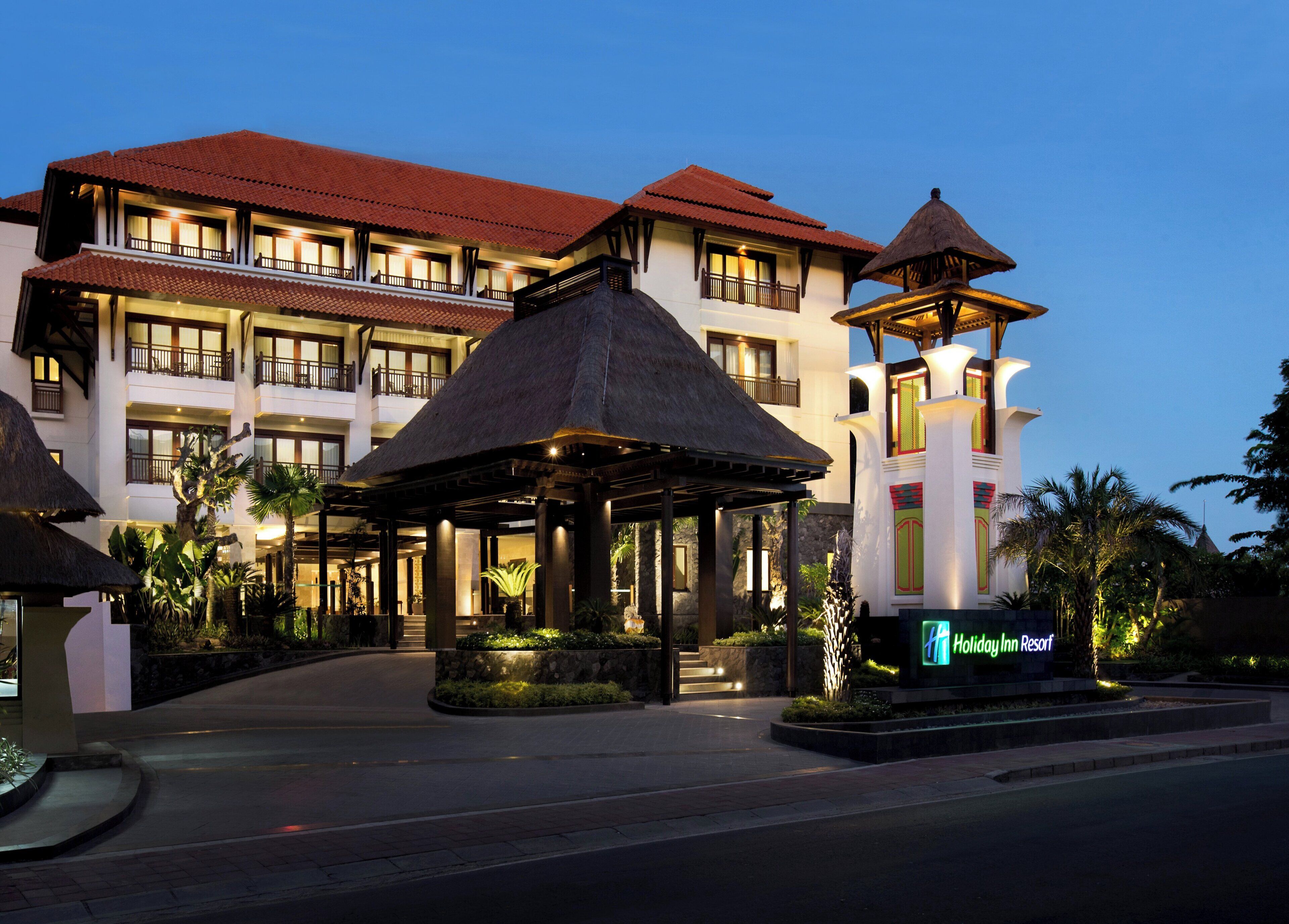Un resort con un edificio grande, una entrada techada y un letrero que indica el nombre.