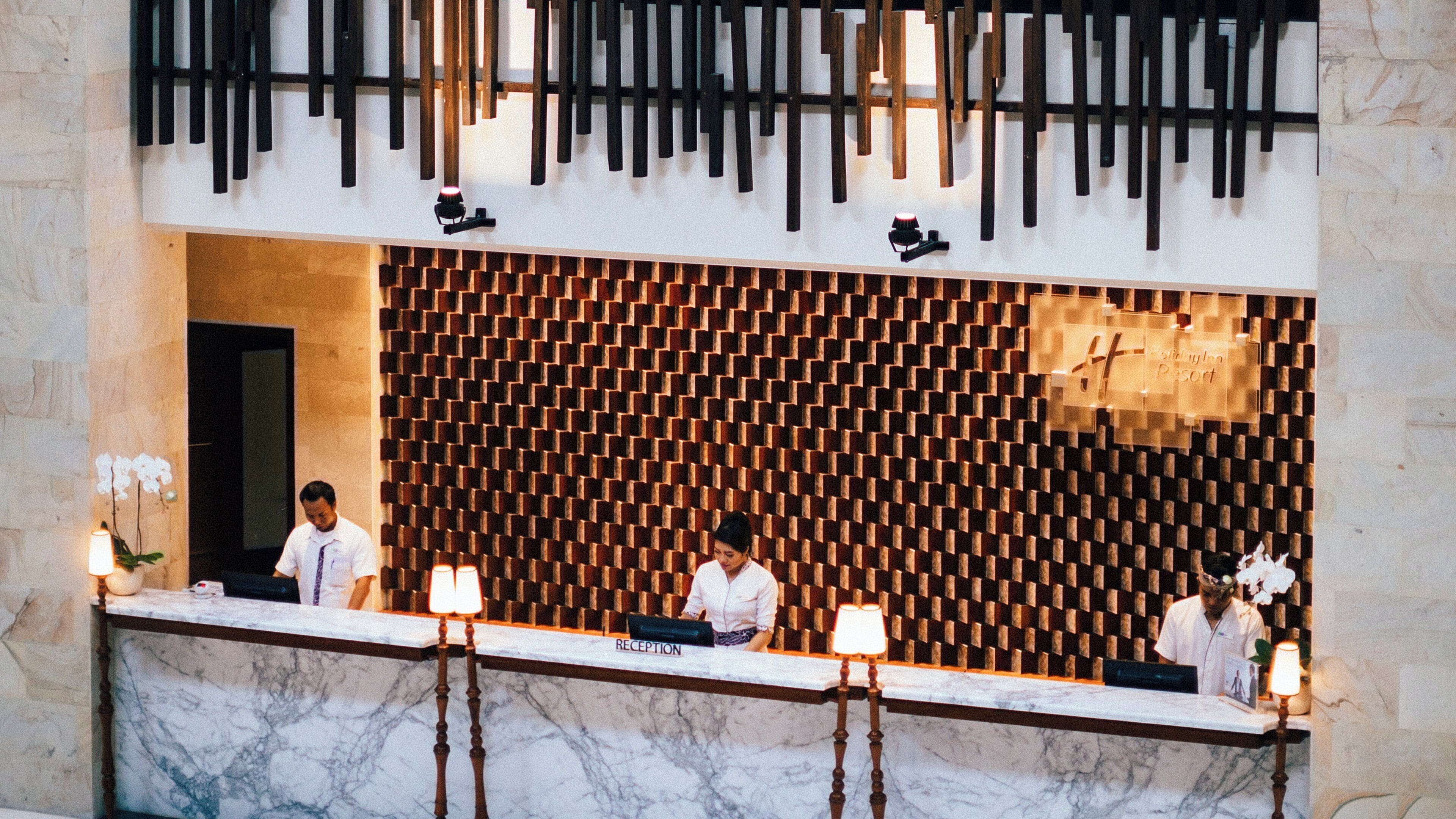 A reception area with a marble counter, a patterned wall, and a sign indicating 'RECEPTION'.