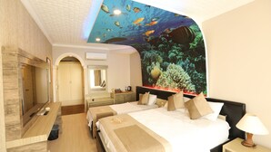 A hotel room with a large bed, a desk, a mirror, and a ceiling mural of an underwater scene. - Unluselek Hotel (Anamur)