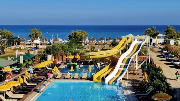 A resort with a pool, multiple water slides, and beach umbrellas. - Unluselek Hotel (Anamur)