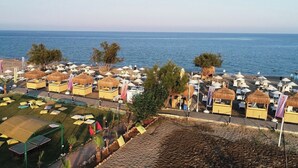 A beachside resort with thatched-roof huts, sun loungers, and a view of the sea. - Unluselek Hotel (Anamur)
