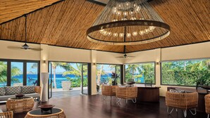 A spacious lounge area with a high ceiling, large windows offering a view of the ocean, and wicker furniture. - Sheraton Resort & Spa, Tokoriki Island, Fiji (Tokoriki Island)