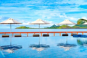 Una piscina al aire libre, sombrillas, sillones reclinables de piscina