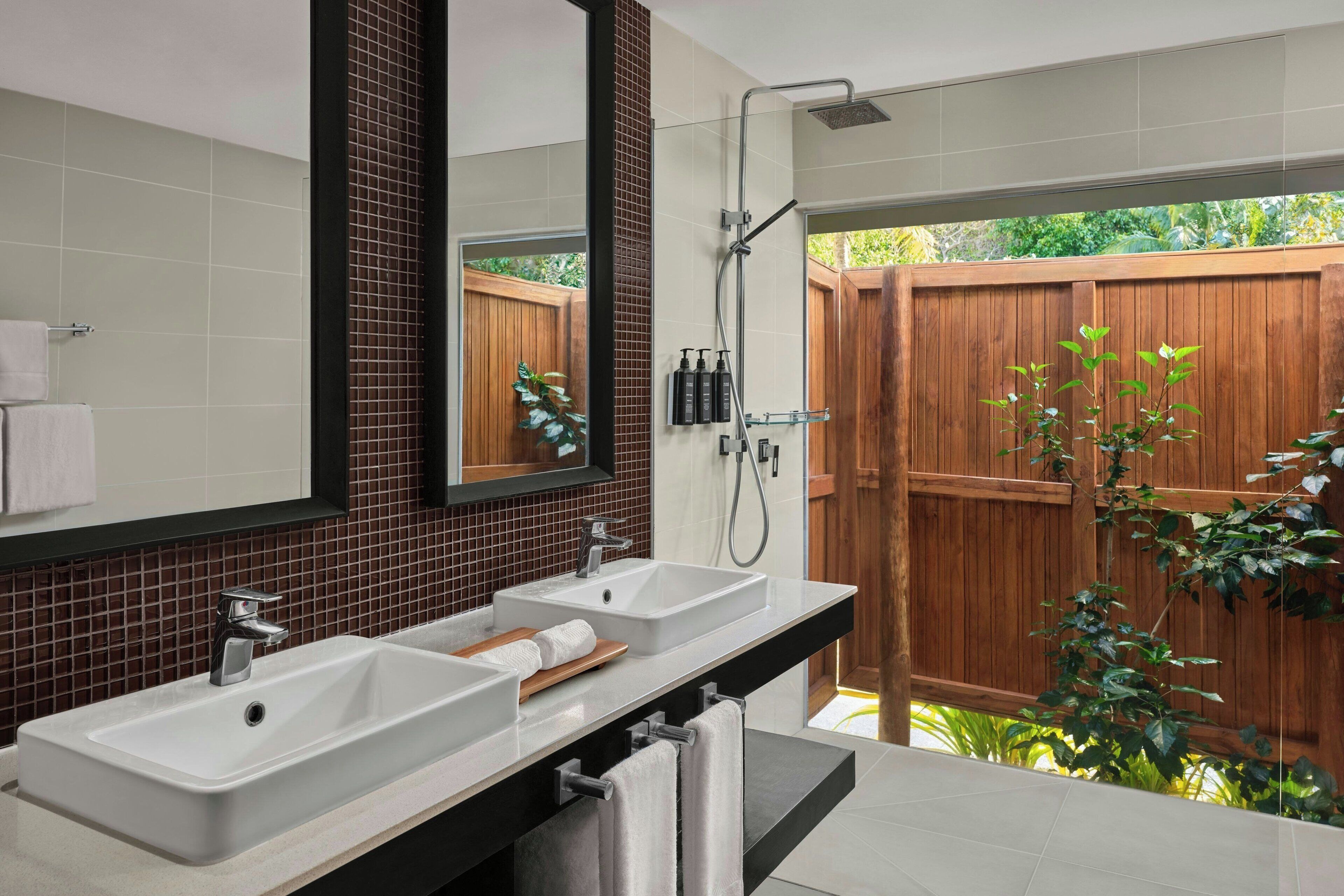 A bathroom with two sinks, a mirror, and a shower.