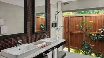 Une salle de bain avec deux lavabos, un miroir et une douche.