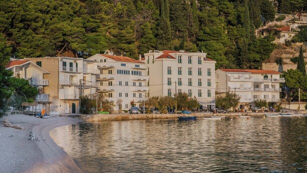 Un ensemble de bâtiments situé sur la côte, doté de nombreux balcons, avec une plage en premier plan.