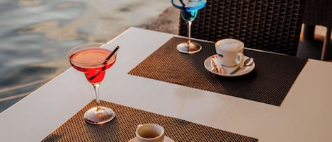 Uma mesa com duas bebidas, uma vermelha e outra azul, e uma chávena de café.