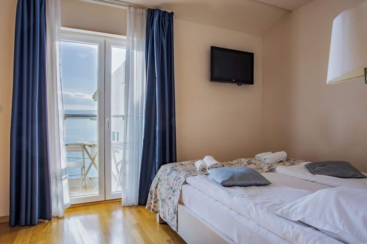 Una habitación de hotel con cama, televisión y balcón con cortinas.