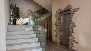 Un intérieur moderne avec un escalier en verre, un mur en pierre et un ascenseur.