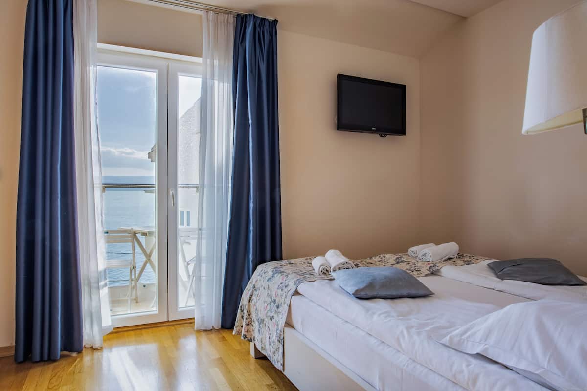 Una habitación de hotel con cama, televisión y balcón con cortinas.