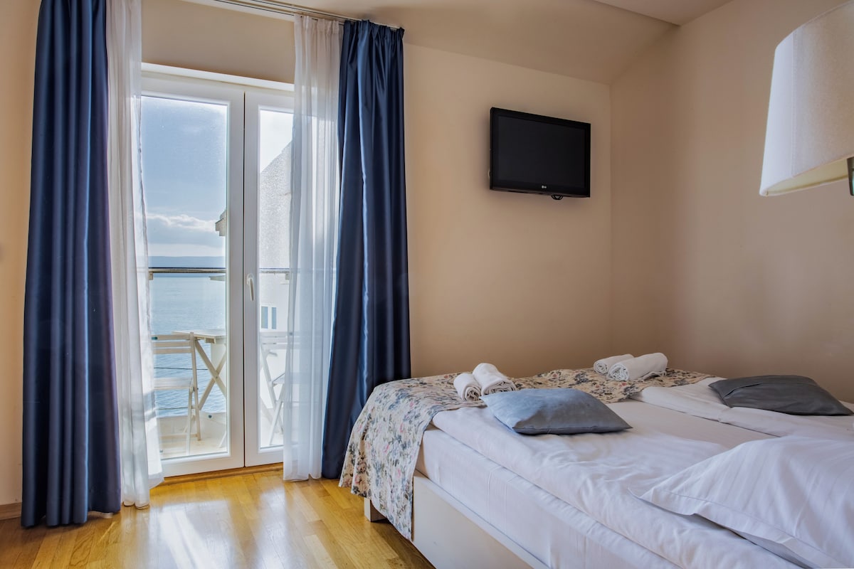 Una habitación de hotel con cama, televisión y balcón con cortinas.