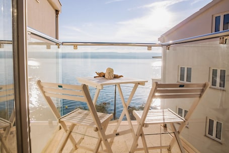 A balcony with a table and chairs, overlooking a body of water.