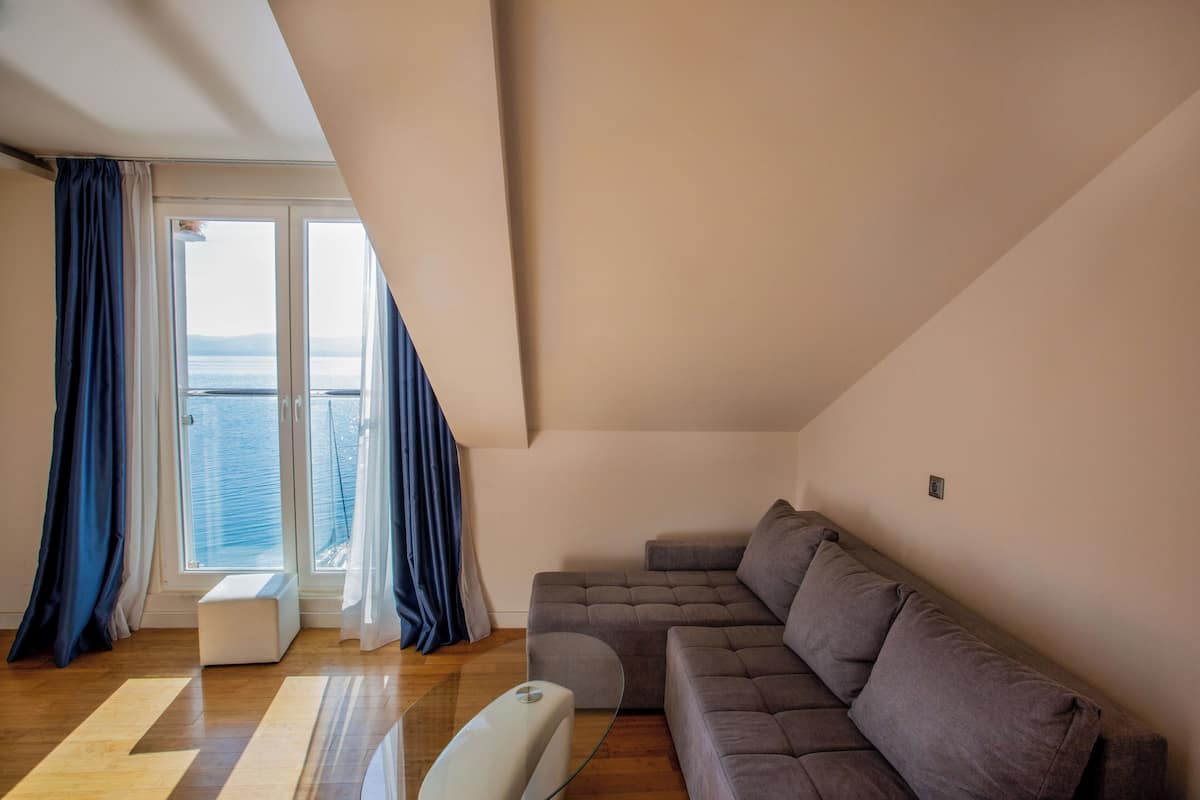 Una sala de estar moderna con un sofá seccional, una mesa de centro de vidrio y vista al mar a través de amplios ventanales.