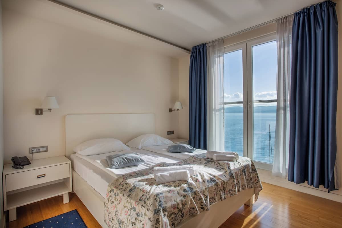 Un dormitorio con cama, mesitas de noche y vista al mar.