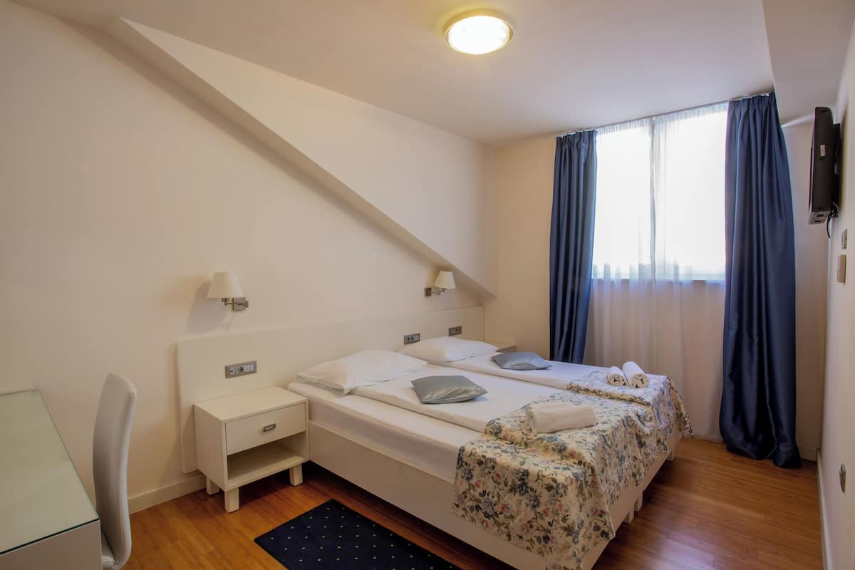 Un dormitorio con dos camas, un escritorio, una silla y una ventana con cortinas.