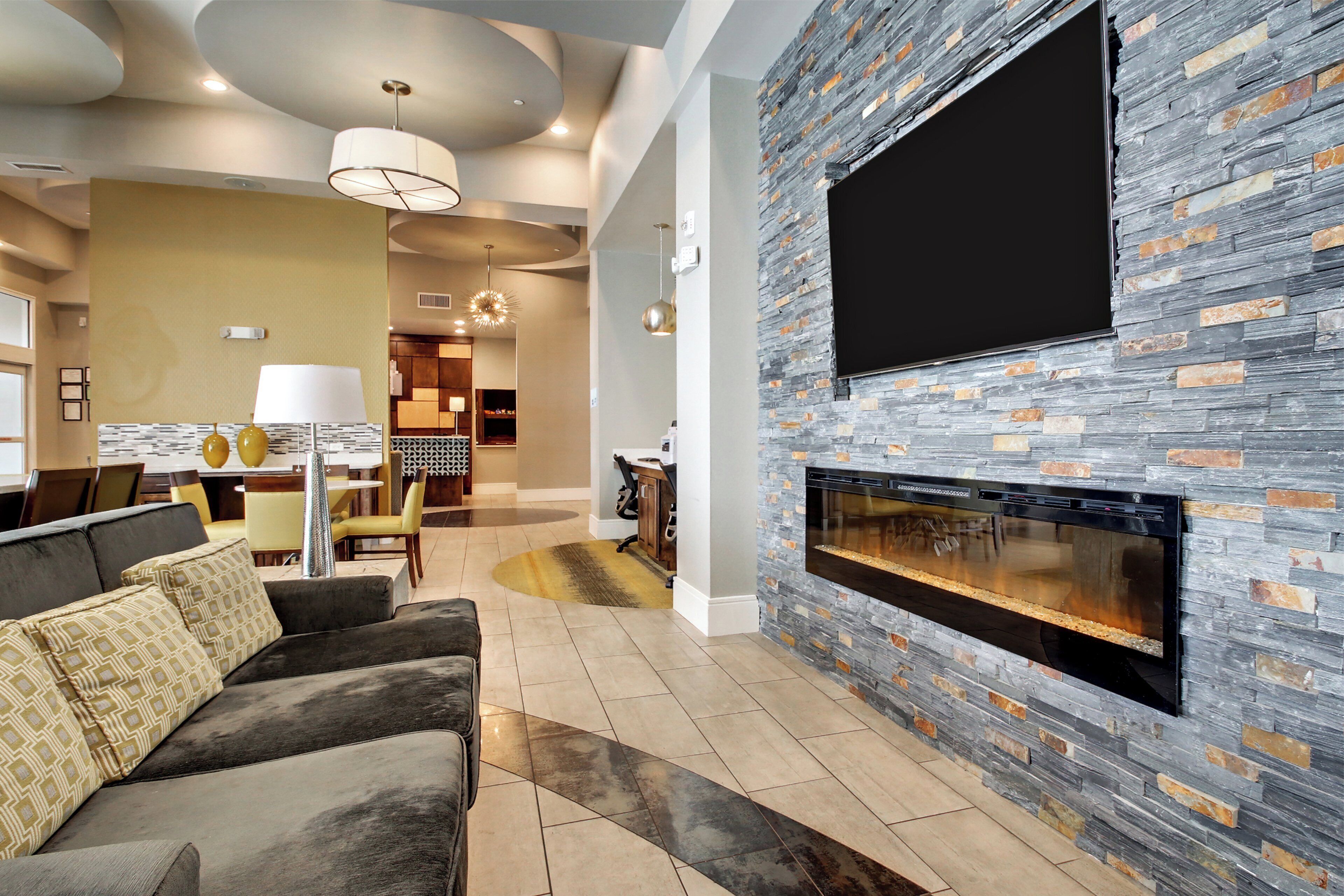 A modern living room with a stone accent wall, a flat-screen TV, and a fireplace.