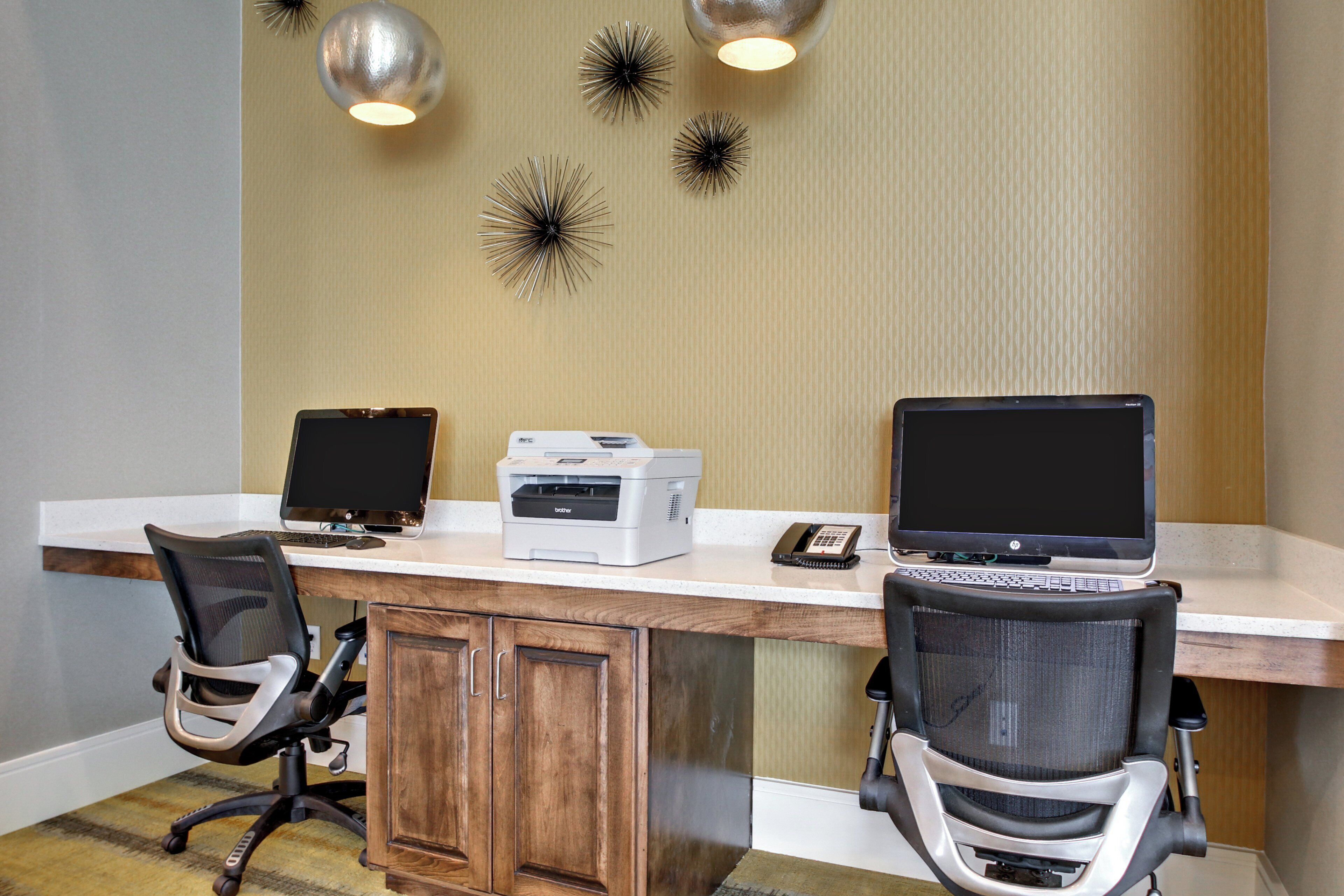 A workspace with two desks, each with a computer, a printer, and office chairs.