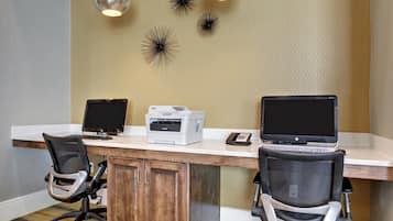 A workspace with two desks, each with a computer, a printer, and office chairs.