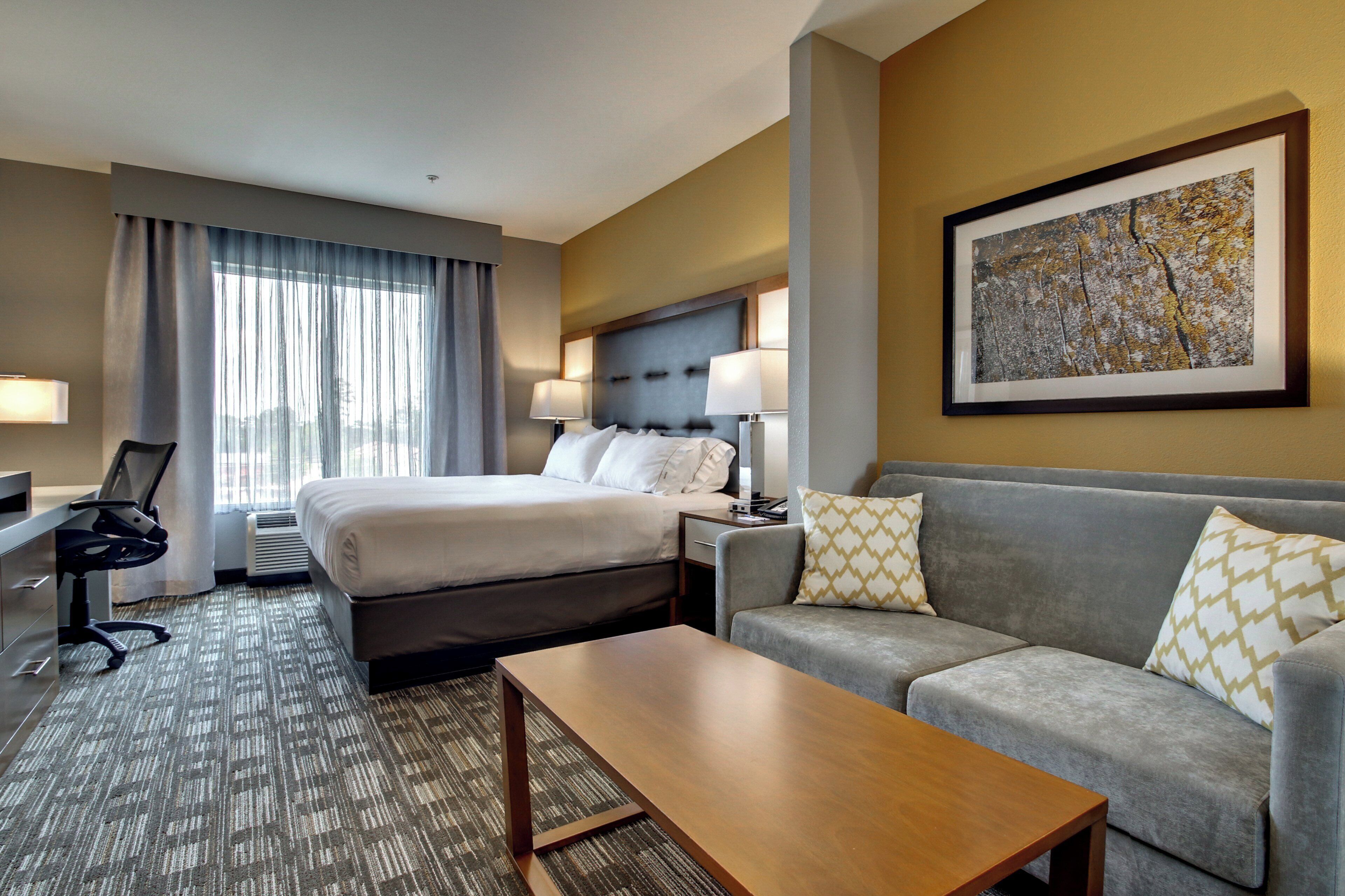 A hotel room with a bed, a sofa, a desk, and a coffee table.