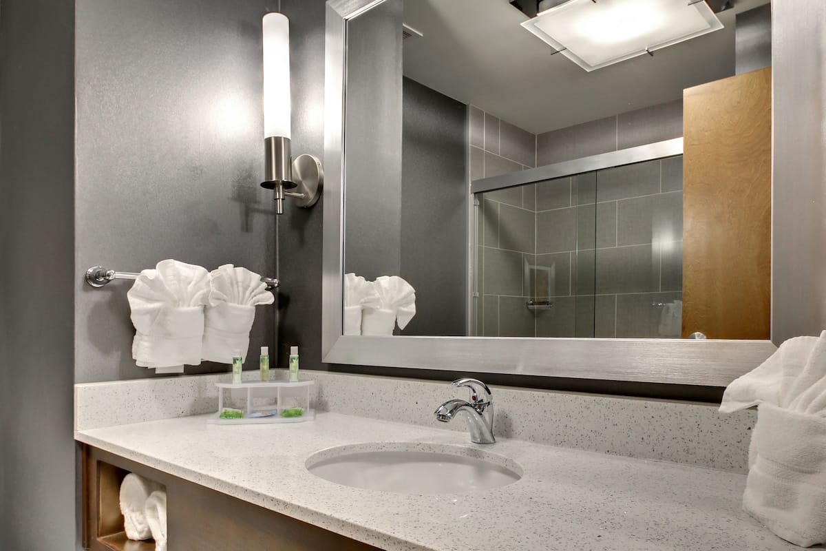 A modern bathroom with a large mirror, a sink, and a towel rack.