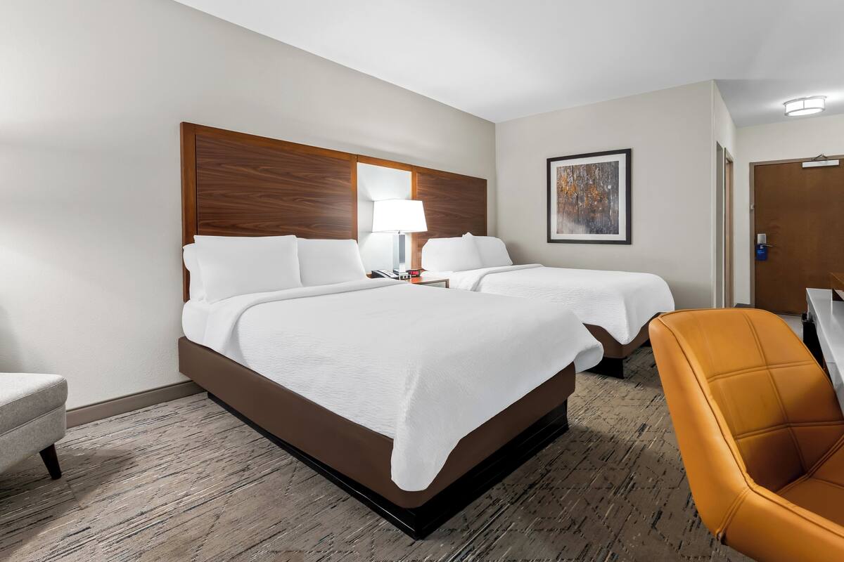 A hotel room with a large bed, two bedside tables, a chair, and a door.